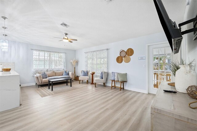 living room with visible vents, a healthy amount of sunlight, light wood-style flooring, and a ceiling fan