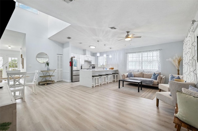 living area with visible vents, light wood-type flooring, and ceiling fan