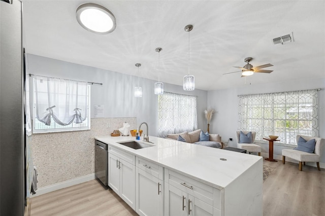 kitchen featuring open floor plan, dishwasher, a peninsula, and a sink