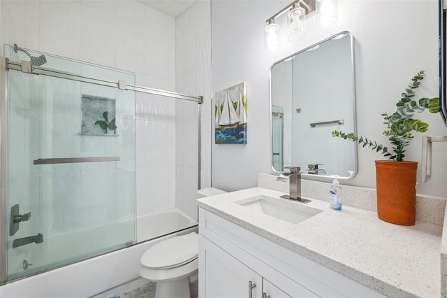 bathroom featuring enclosed tub / shower combo, toilet, and vanity