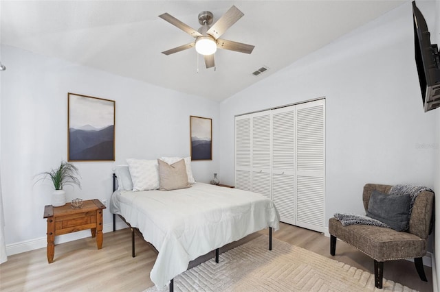 bedroom featuring visible vents, light wood-style flooring, ceiling fan, vaulted ceiling, and a closet