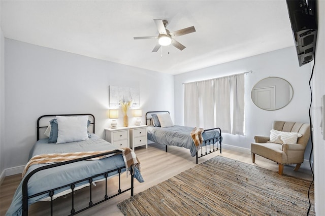 bedroom featuring baseboards, wood finished floors, and a ceiling fan