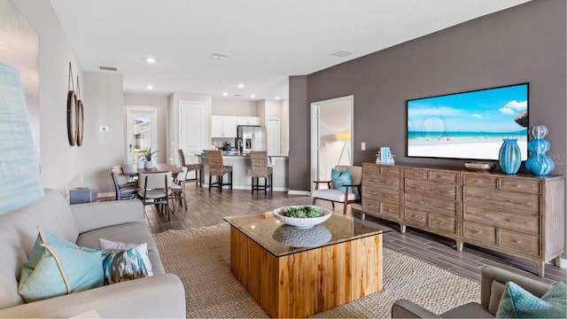 living room featuring recessed lighting, visible vents, baseboards, and wood finished floors