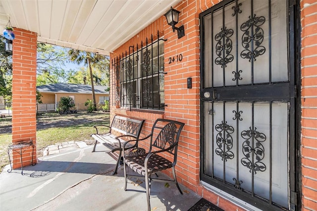 entrance to property featuring brick siding and covered porch