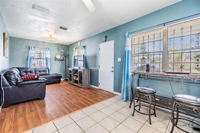 tiled living room featuring plenty of natural light, baseboards, and visible vents