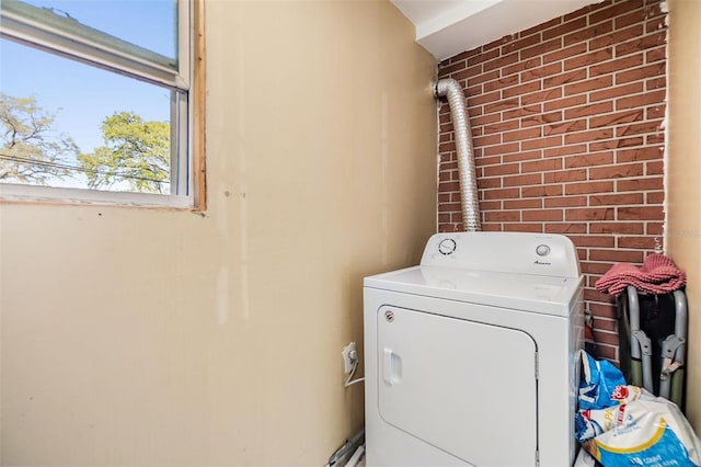 laundry area with washer / dryer, brick wall, and laundry area