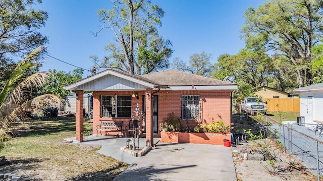 view of front of home with a front yard, covered porch, fence, and brick siding