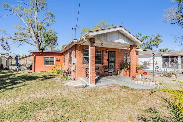 back of house featuring fence, a lawn, and brick siding