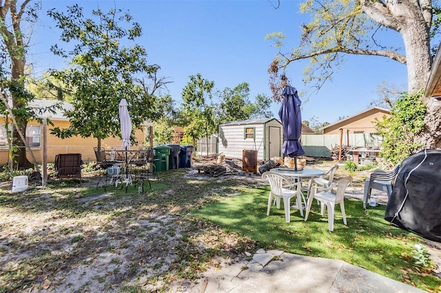 view of yard featuring an outbuilding, a storage shed, and fence