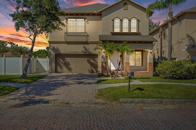 mediterranean / spanish home featuring a garage, a gate, brick siding, and stucco siding