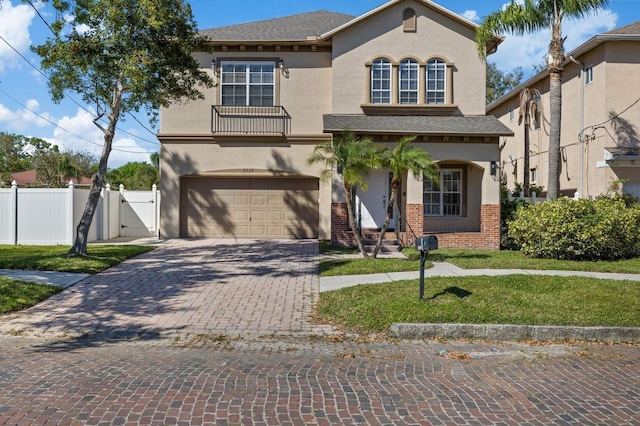 view of front facade with decorative driveway, brick siding, stucco siding, a gate, and fence