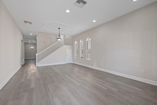 unfurnished living room with stairway, visible vents, and wood finished floors