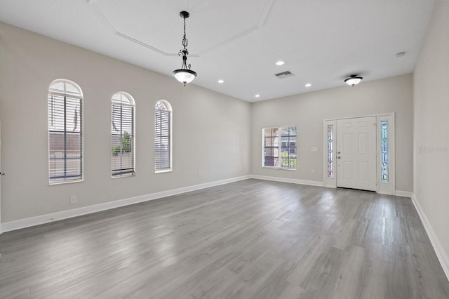 entrance foyer with baseboards, plenty of natural light, visible vents, and wood finished floors