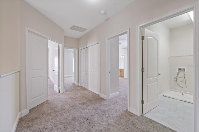 corridor featuring carpet floors, visible vents, and baseboards