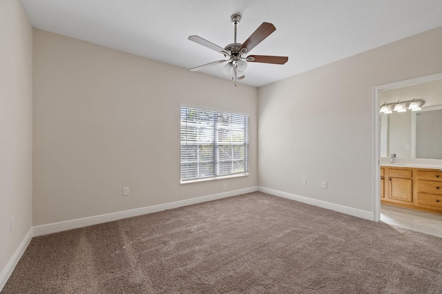 unfurnished bedroom with light colored carpet, a ceiling fan, a sink, ensuite bath, and baseboards