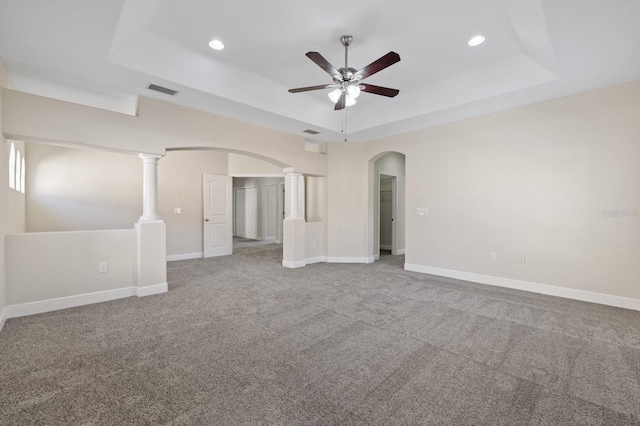 unfurnished room featuring baseboards, arched walkways, a raised ceiling, and carpet flooring