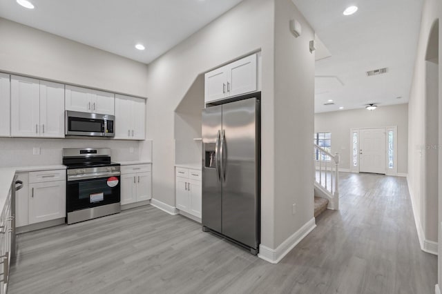 kitchen with visible vents, white cabinets, light wood-style flooring, stainless steel appliances, and light countertops