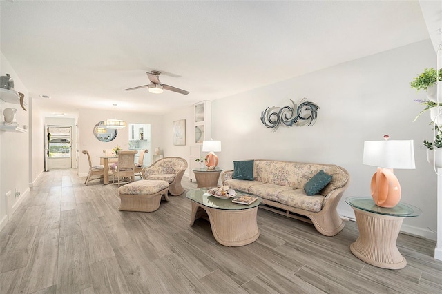 living room featuring light wood-style floors, baseboards, and a ceiling fan