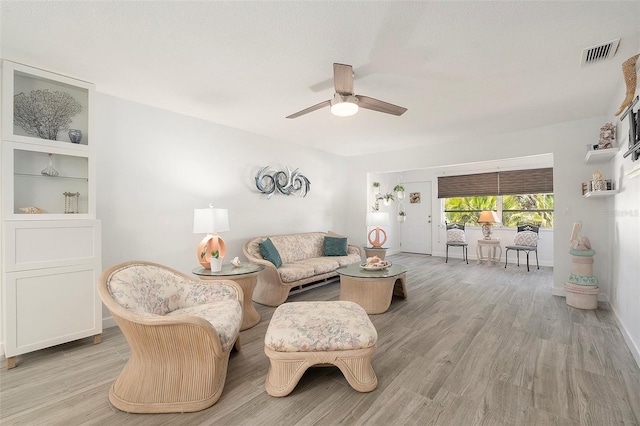 living room featuring baseboards, wood finished floors, visible vents, and a ceiling fan