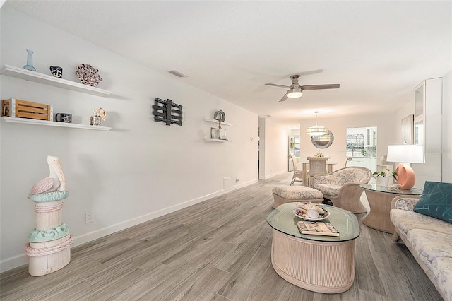 living room with baseboards, visible vents, ceiling fan, and wood finished floors