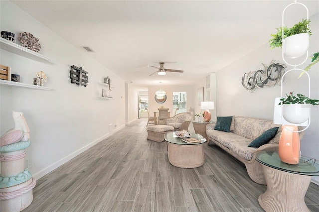 living area with baseboards, visible vents, ceiling fan, and wood finished floors