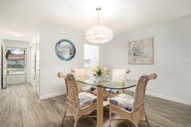 dining space with light wood-type flooring and baseboards