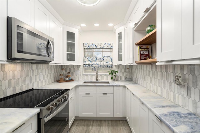 kitchen with electric range, stainless steel microwave, white cabinetry, open shelves, and a sink