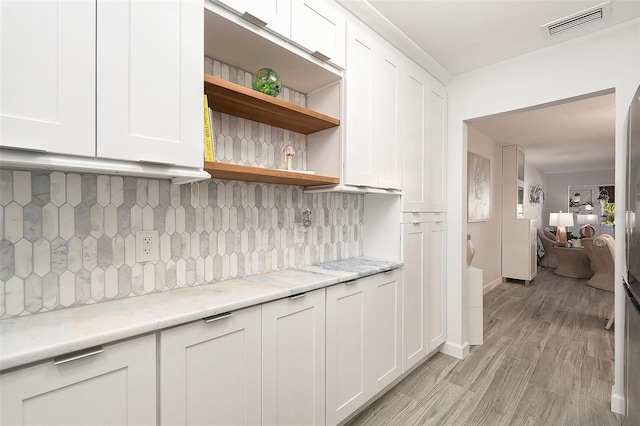 kitchen featuring light stone counters, visible vents, white cabinets, backsplash, and open shelves