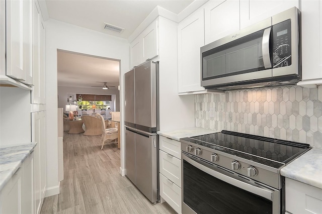 kitchen featuring stainless steel appliances, visible vents, white cabinets, and backsplash