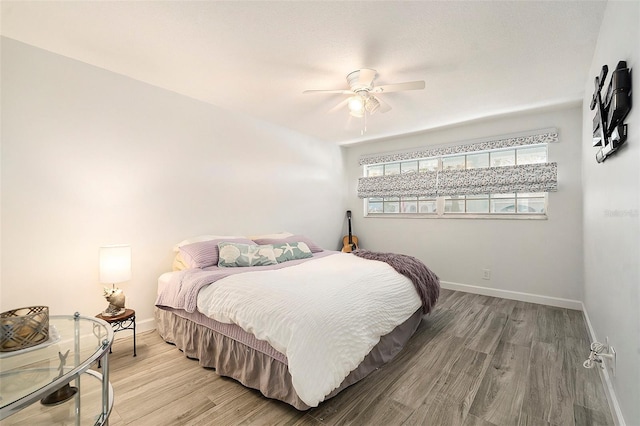 bedroom featuring light wood finished floors, a ceiling fan, and baseboards