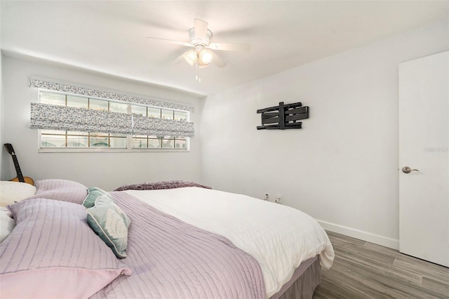 bedroom with ceiling fan, wood finished floors, and baseboards