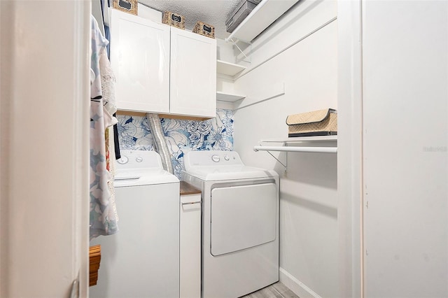 laundry room featuring cabinet space, light wood-style flooring, and washer and clothes dryer