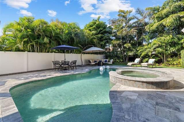 view of swimming pool with a patio area, a pool with connected hot tub, fence, and an outdoor living space