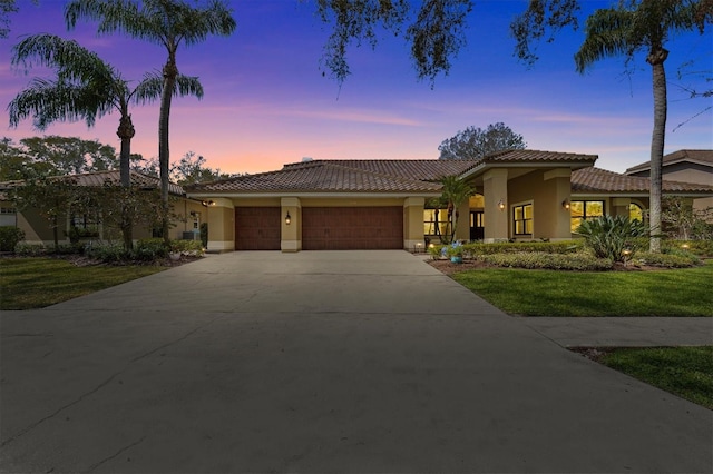 mediterranean / spanish-style home featuring driveway, an attached garage, a tiled roof, and stucco siding