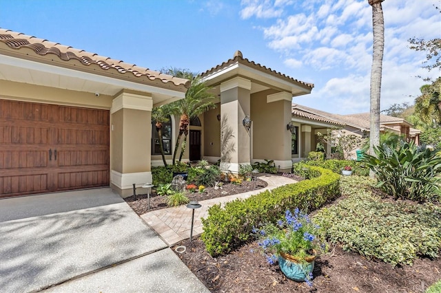 view of exterior entry featuring driveway, a tile roof, and stucco siding