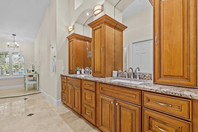 bathroom featuring a chandelier, a sink, baseboards, and double vanity