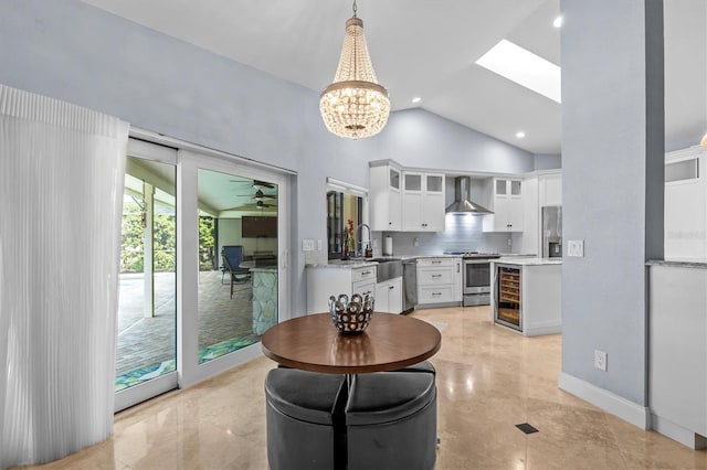 dining area featuring wine cooler, recessed lighting, high vaulted ceiling, baseboards, and ceiling fan with notable chandelier