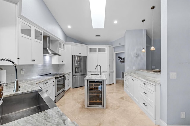 kitchen featuring a skylight, beverage cooler, appliances with stainless steel finishes, wall chimney range hood, and a sink