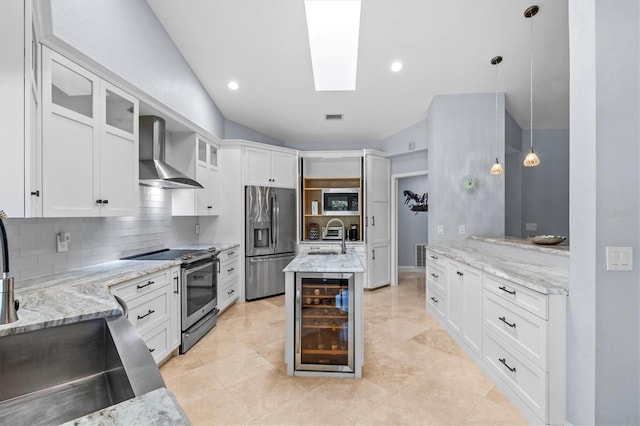 kitchen with wine cooler, a skylight, stainless steel appliances, tasteful backsplash, and wall chimney range hood