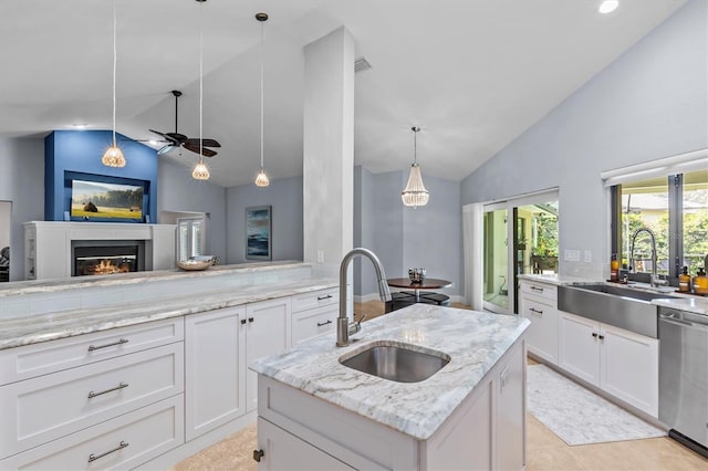 kitchen with dishwasher, a glass covered fireplace, a sink, and lofted ceiling