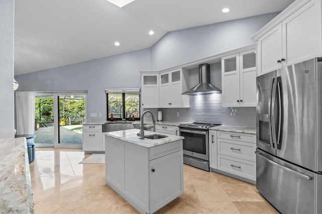 kitchen featuring appliances with stainless steel finishes, light stone countertops, a kitchen island with sink, wall chimney range hood, and a sink