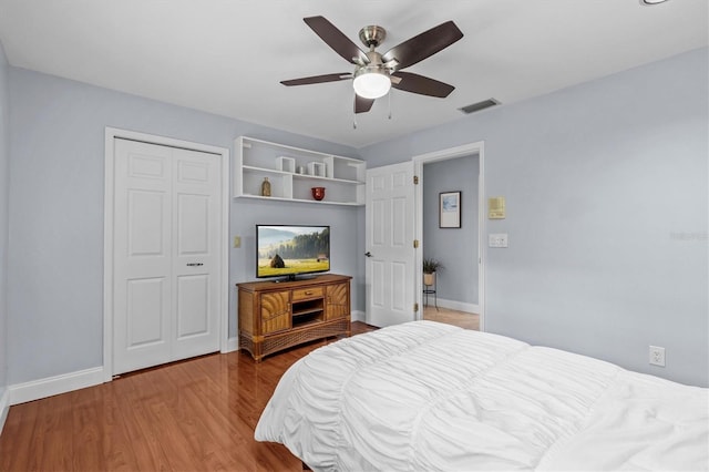 bedroom featuring baseboards, a closet, visible vents, and wood finished floors