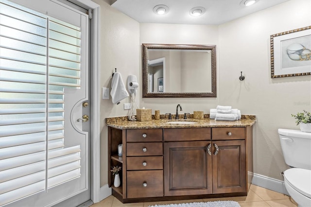 bathroom with toilet, vanity, baseboards, and tile patterned floors