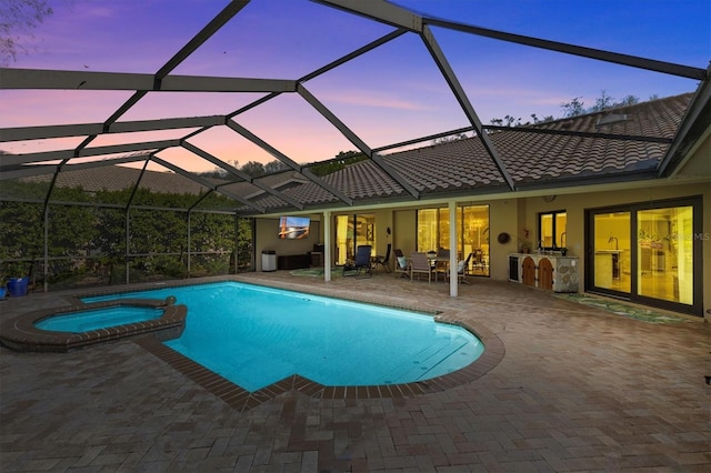 view of swimming pool with glass enclosure, a pool with connected hot tub, and a patio