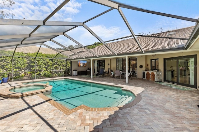 view of swimming pool with a patio area, a pool with connected hot tub, glass enclosure, and area for grilling