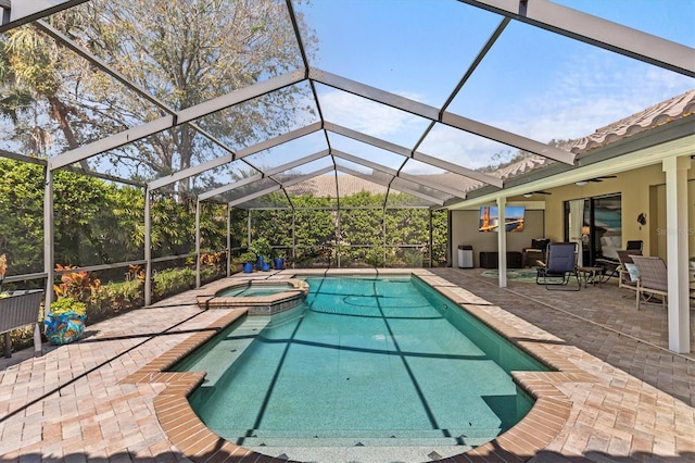 view of swimming pool featuring a pool with connected hot tub, a patio, a lanai, and ceiling fan