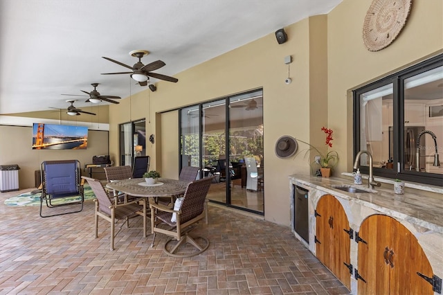 view of patio / terrace featuring ceiling fan, an outdoor kitchen, a sink, and outdoor dining space