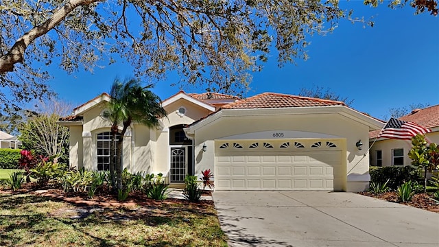 mediterranean / spanish-style home featuring a tile roof, an attached garage, driveway, and stucco siding