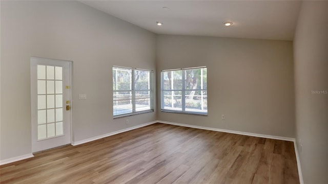 empty room with vaulted ceiling, recessed lighting, wood finished floors, and baseboards