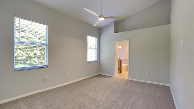 unfurnished bedroom featuring high vaulted ceiling, ensuite bathroom, carpet flooring, baseboards, and ceiling fan